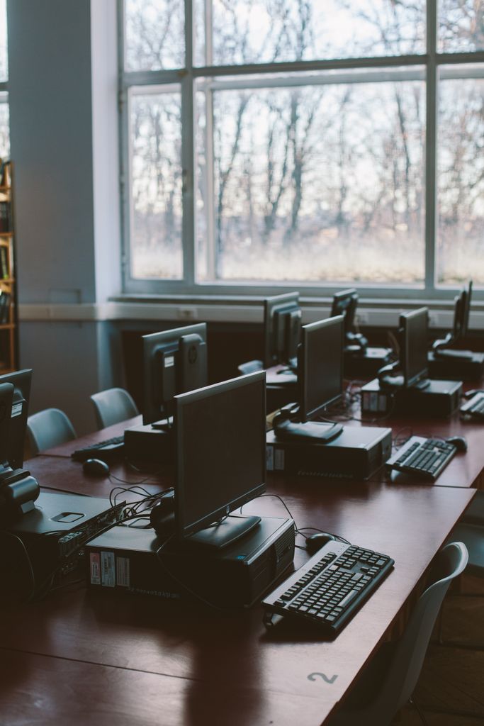 Spacious computer lab with rows of monitors and keyboards in a sunlit room.